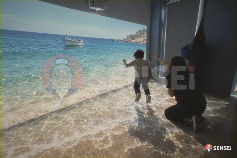 Un bambino salta tra le onde di una spiaggia proiettata sul pavimento mentre un'operatrice indica la barca sulla parete